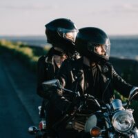 couple of bikers in helmets riding classical motorcycle on country road