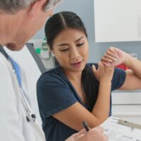 Woman with rotator cuff injury listening to doctor explain treatment options Woman with rotator cuff injury listening to doctor explain treatment options