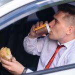 Business man drinking coffee and eat in the car.