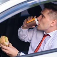 Business man drinking coffee and eat in the car.