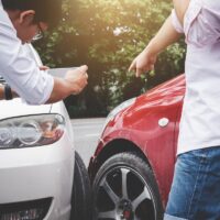 Two drivers man arguing after a car traffic accident collision and making phone call to Insurance Agent and take a photo, Traffic Accident and insurance concept