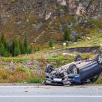 Car accident place on a bend, overturned car lies on the roof